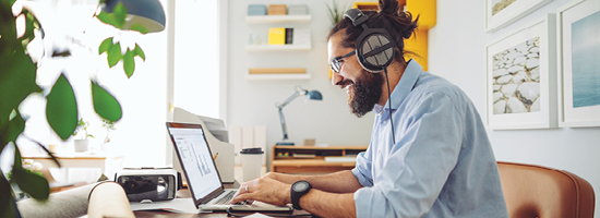 A man with his hair in a bun chats on the computer
