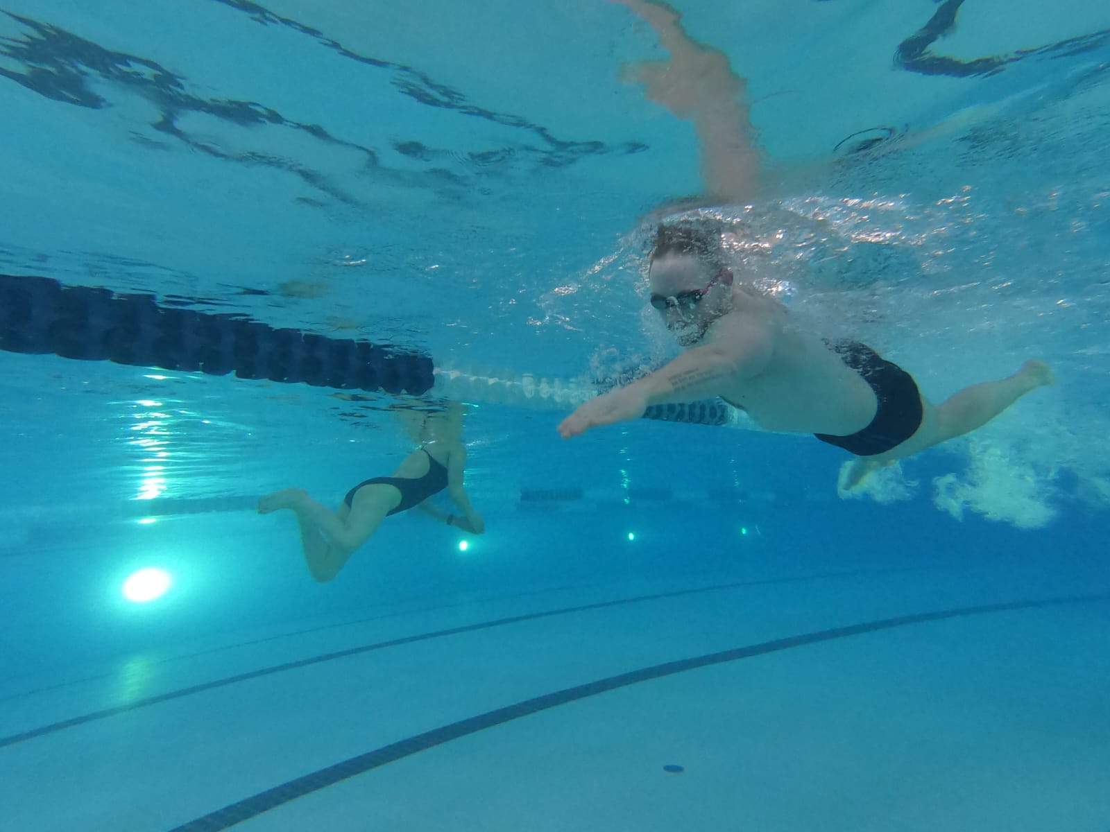 Two swimmers doing laps in a pool, taken from under water 