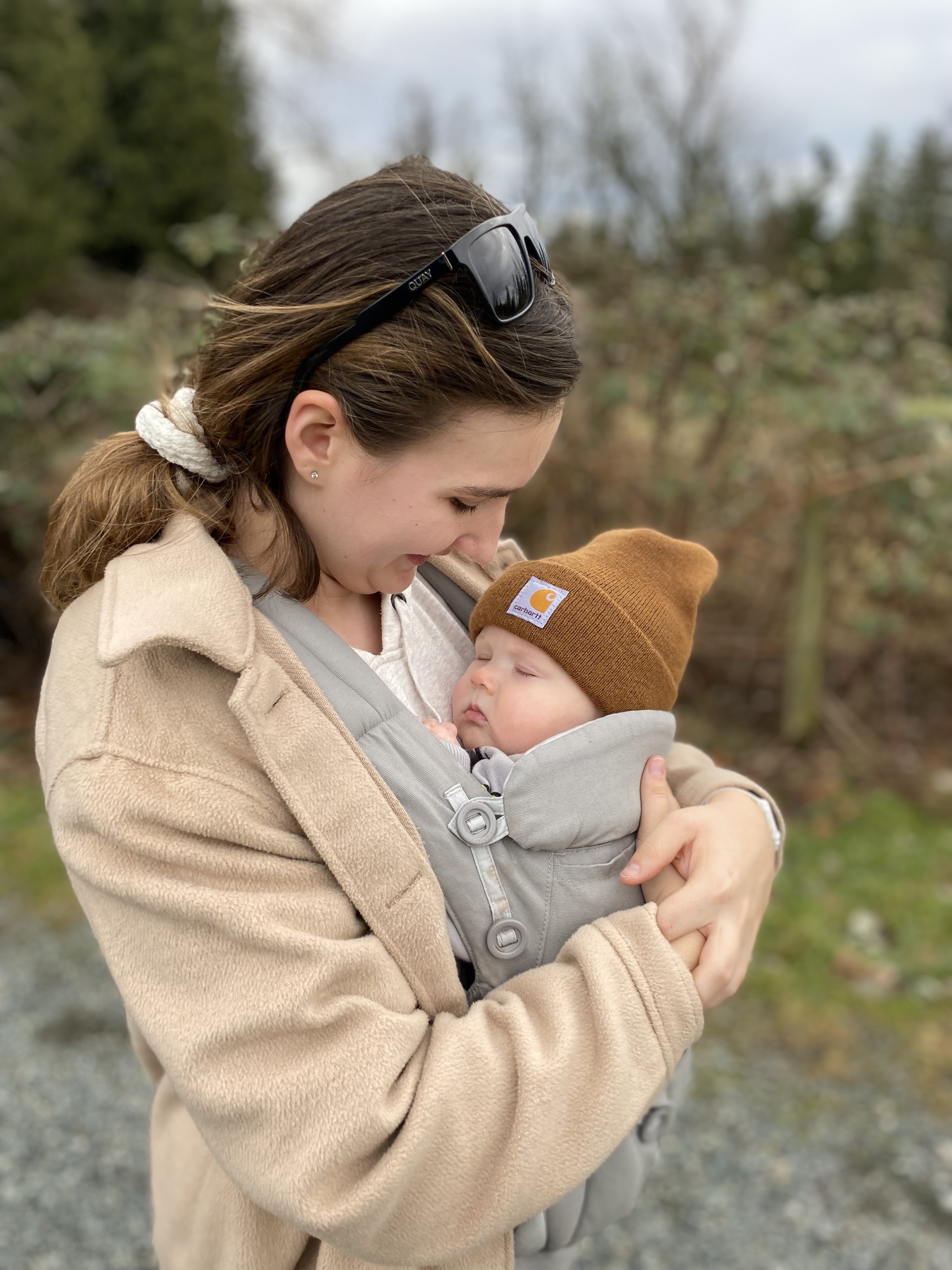 Woman smiling down at baby in a baby carrier on chest